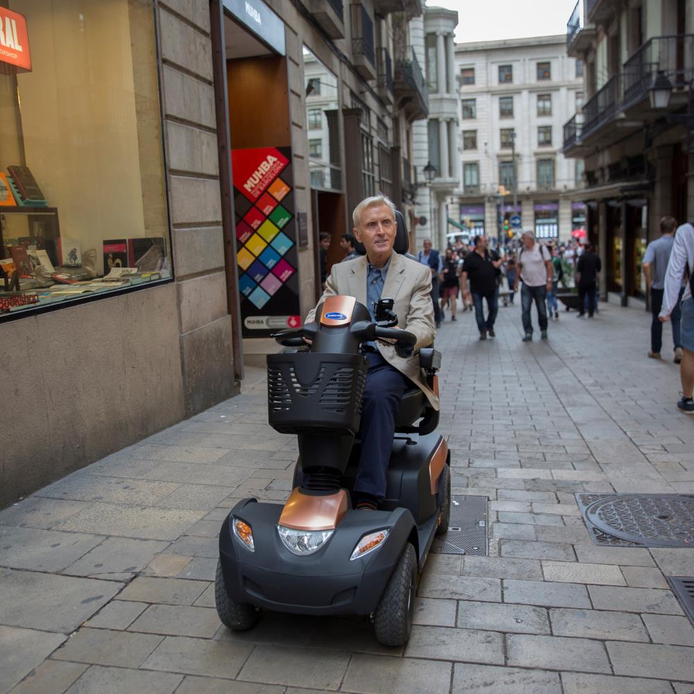 Invacare Comet Pro - Man driving mobility scooter around town.